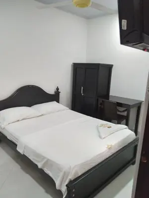 a bedroom with a bed with a black headboard and a table at HOTEL DORADO PUERTO BERRIO in Puerto Berrío