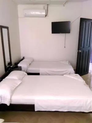 three beds in a room with a flat screen tv at HOTEL DORADO PUERTO BERRIO in Puerto Berrío