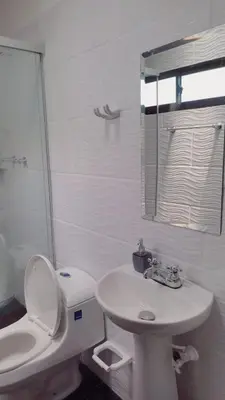 a white bathroom with a toilet and a sink at AMPLIO APARTAMENTO AMOBLADO SECTOR LAURELES-ESTADIO Paris in Medellín
