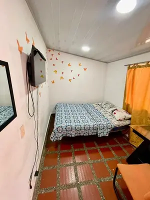 a small room with a bed and a tv at Hostel Urban City Medellin in Medellín