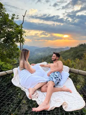 a man and a woman sitting on a bed on top of a mountain at Nazca Glamping in Villamaría
