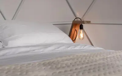 a bed with a white pillow and a light on it at Nazca Glamping in Villamaría