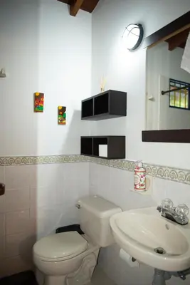 a white bathroom with a toilet and a sink at FINCA HOTEL CARMONIA DEL BOSQUE in Venecia