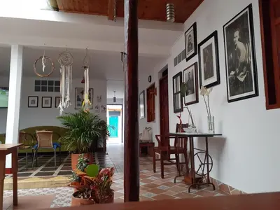 a living room with a table and some pictures on the wall at Hostal La Comedia in Jardin