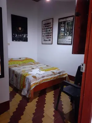 a bedroom with a bed and a chair and posters at Hostal La Comedia in Jardin