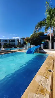 a swimming pool with blue water and palm trees at Apartasol Ciudadela Santafe - Santa Fe de Antioquia in Santa Fe de Antioquia
