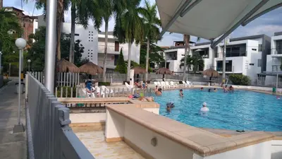 a swimming pool with people in the water at Apartasol Ciudadela Santafe - Santa Fe de Antioquia in Santa Fe de Antioquia