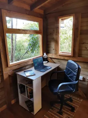 a desk with a laptop and a chair in a cabin at La Cabaña de Huckleberry in El Retiro