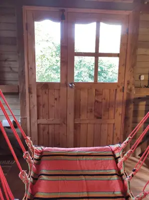 a hammock in a room with two windows and a door at La Cabaña de Huckleberry in El Retiro