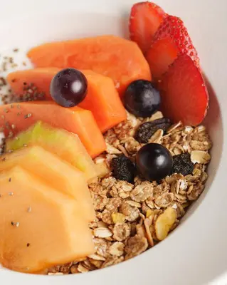 a bowl of granola and fruit on a plate at Hashtag 98 Hotel By Jalo in Medellín