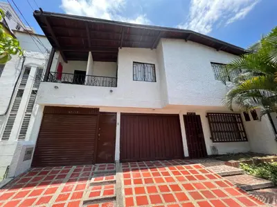 a house with two garage doors and a palm tree at APARTAMENTO AMOBLADO SECTOR LAURELES-ESTADIO hasta 8 personas - Londres in Medellín
