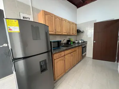 a kitchen with a stainless steel refrigerator and wooden cabinets at APARTAMENTO AMOBLADO SECTOR LAURELES-ESTADIO hasta 6 personas - Praga in Medellín