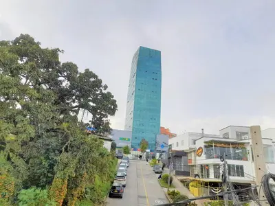 a tall blue building on a city street with cars at Casa Jaguar Manizales sector Cable in Manizales