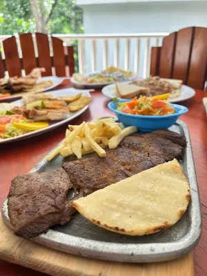 a table with a plate of food with meat and chips at Eco hotel el bosque in Doradal
