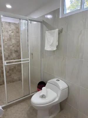 a bathroom with a white toilet and a shower at Eco hotel el bosque in Doradal