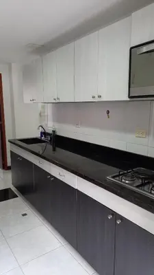 a kitchen with white cabinets and a black counter top at Apartamento remodelado enLaureles 300mbps internet in Medellín