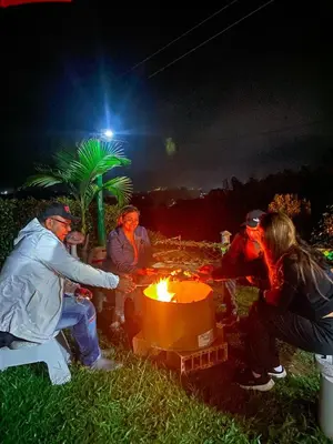 a group of people sitting around a table with a fire at Finca Palma de Coco, Municipio de el Peñol Antioquia in El Peñol