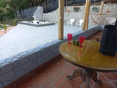 a table with two red wine glasses on a patio at Finca Palma de Coco, Municipio de el Peñol Antioquia in El Peñol