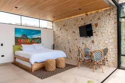 a bedroom with a bed and a stone wall at Villa al lado de la represa de Guatapé con jacuzzi y cancha de tennis privada in El Peñol