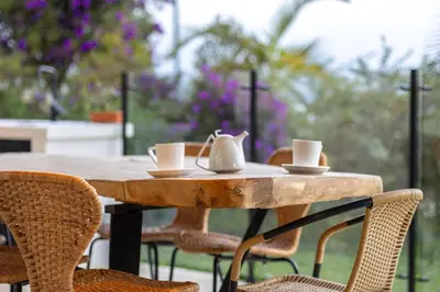 a wooden table with chairs and tea cups on it at Villa al lado de la represa de Guatapé con jacuzzi y cancha de tennis privada in El Peñol
