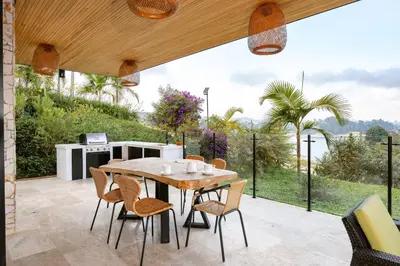 a patio with a table and chairs and a kitchen at Villa al lado de la represa de Guatapé con jacuzzi y cancha de tennis privada in El Peñol