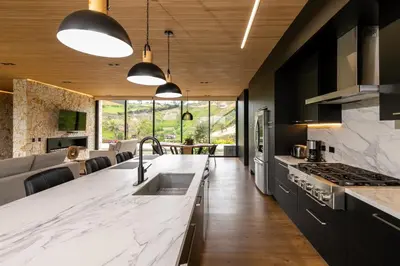 a kitchen with white marble countertops and black cabinets at Villa al lado de la represa de Guatapé con jacuzzi y cancha de tennis privada in El Peñol