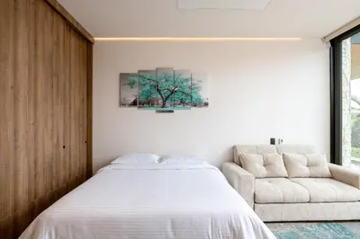 a bedroom with a bed and a chair at Villa al lado de la represa de Guatapé con jacuzzi y cancha de tennis privada in El Peñol