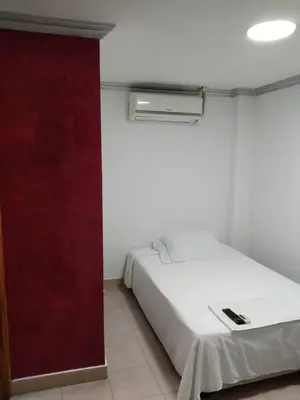 a bedroom with a white bed and a red wall at Hotel Kariary in Puerto Boyacá