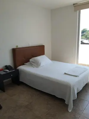 a bedroom with a large white bed and a window at Hotel Kariary in Puerto Boyacá