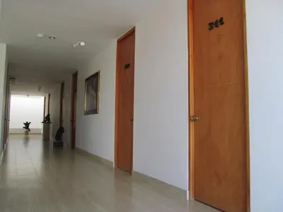 an empty hallway with wooden doors and white walls at Hotel Kariary in Puerto Boyacá