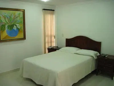 a bedroom with a bed and a painting on the wall at Hotel Kariary in Puerto Boyacá
