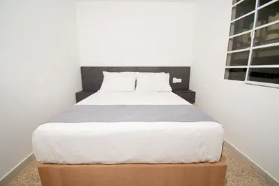 a bedroom with a large bed with a brown box at Brana by Bernalo Hotels in Medellín