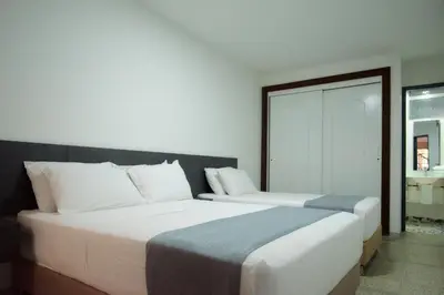 two beds in a hotel room with a mirror at Brana by Bernalo Hotels in Medellín