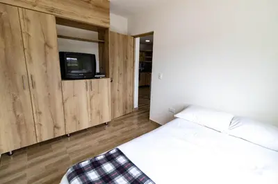 a bedroom with a bed and a tv on a wall at Vista montaña Guatape by Hope in Guatapé