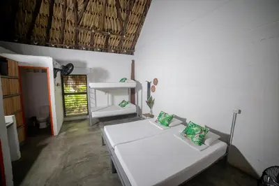 a room with two white beds in a room at Makenke Hostel By Los Colores Ecoparque in Doradal