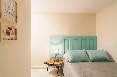 a bedroom with a bed with a green headboard and a table at Rinconcito Encantador in Medellín