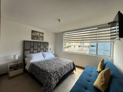 a bedroom with a bed and a couch and a window at MARGARETH in Manizales