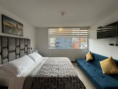 a bedroom with a large bed and a blue couch at MARGARETH in Manizales