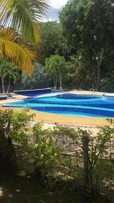 a blue swimming pool with trees in the background at Cabaña con aire acondicionado San Jeronimo in San Jerónimo