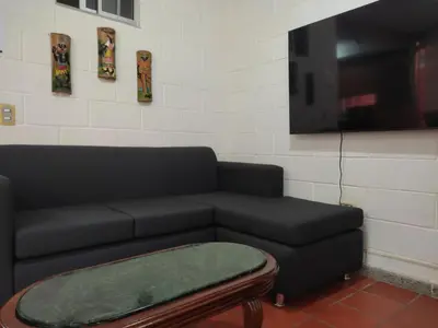 a living room with a black couch and a table at Cabaña con aire acondicionado San Jeronimo in San Jerónimo