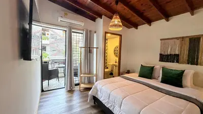 a bedroom with a bed and a door to a patio at Luum Casa Hotel Manila in Medellín