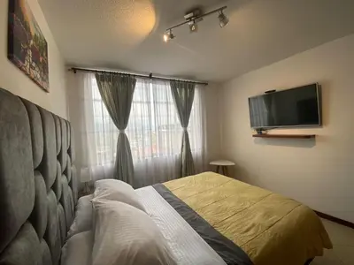 a bedroom with a bed and a flat screen tv at KOROLOVA in Manizales