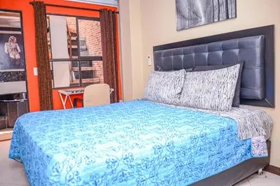 a bedroom with a large bed with a blue comforter at Calle 8 Suites in Medellín