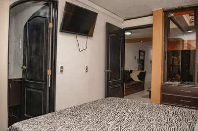 a bedroom with a bed and a flat screen tv at Calle 8 Suites in Medellín