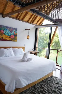 a bedroom with a white bed and a large window at Ibuku Hotel Guatapé - Chalets in Guatapé