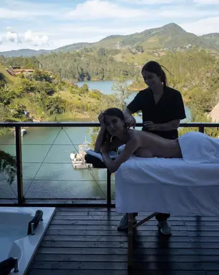 a woman sitting on a bed on a balcony at Ibuku Hotel Guatapé - Chalets in Guatapé