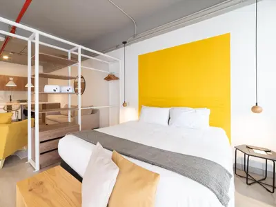 a bedroom with a white bed and a yellow wall at Lauret Lofts by Wynwood House in Medellín