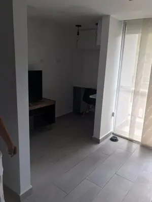 an empty living room with a television and a desk at Andy in Bello
