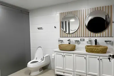 a bathroom with a toilet and two sinks and a mirror at Apt Palos Altos Poblado; caminando de restaurantes in Medellín