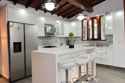 a kitchen with white cabinets and a counter with stools at Apt Palos Altos Poblado; caminando de restaurantes in Medellín